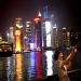 Une touriste chinoise se prend en photo devant les lumières des gratte-ciel du nouveau district de Pudong à Shanghai